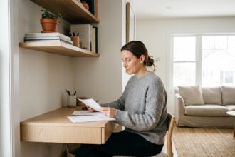 Femme travaillant à un bureau compact intégré dans un coin salon, avec étagères en bois et décor épuré