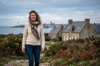 Femme souriante marchant sur un sentier breton au bord de l'Atlantique